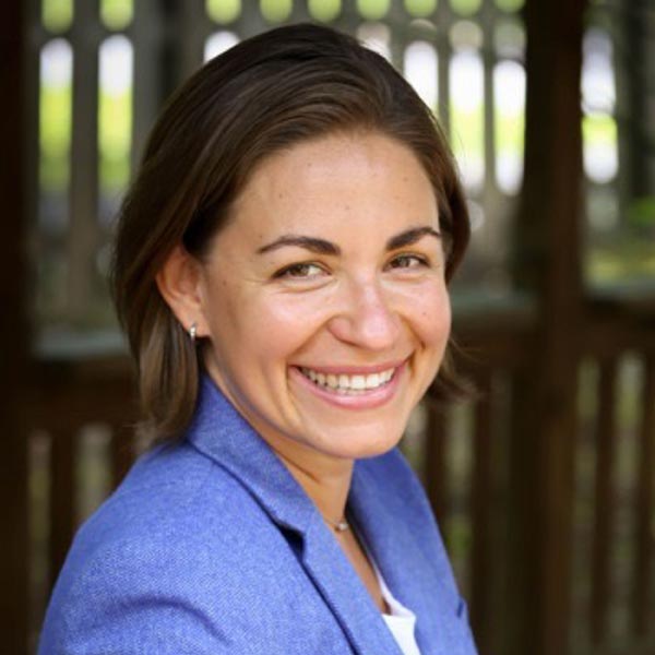 Headshot of Katie Curran, MAPP. Katie is smiling with short dark brown hair and a blue blazer with a white shirt