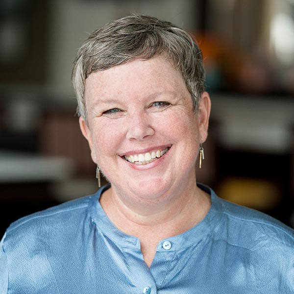Headshot of Patricia Wright, PhD, MPH. Patrica is smiling and has very short medium gray hair and blue-gray eyes and a blue button up shirt.