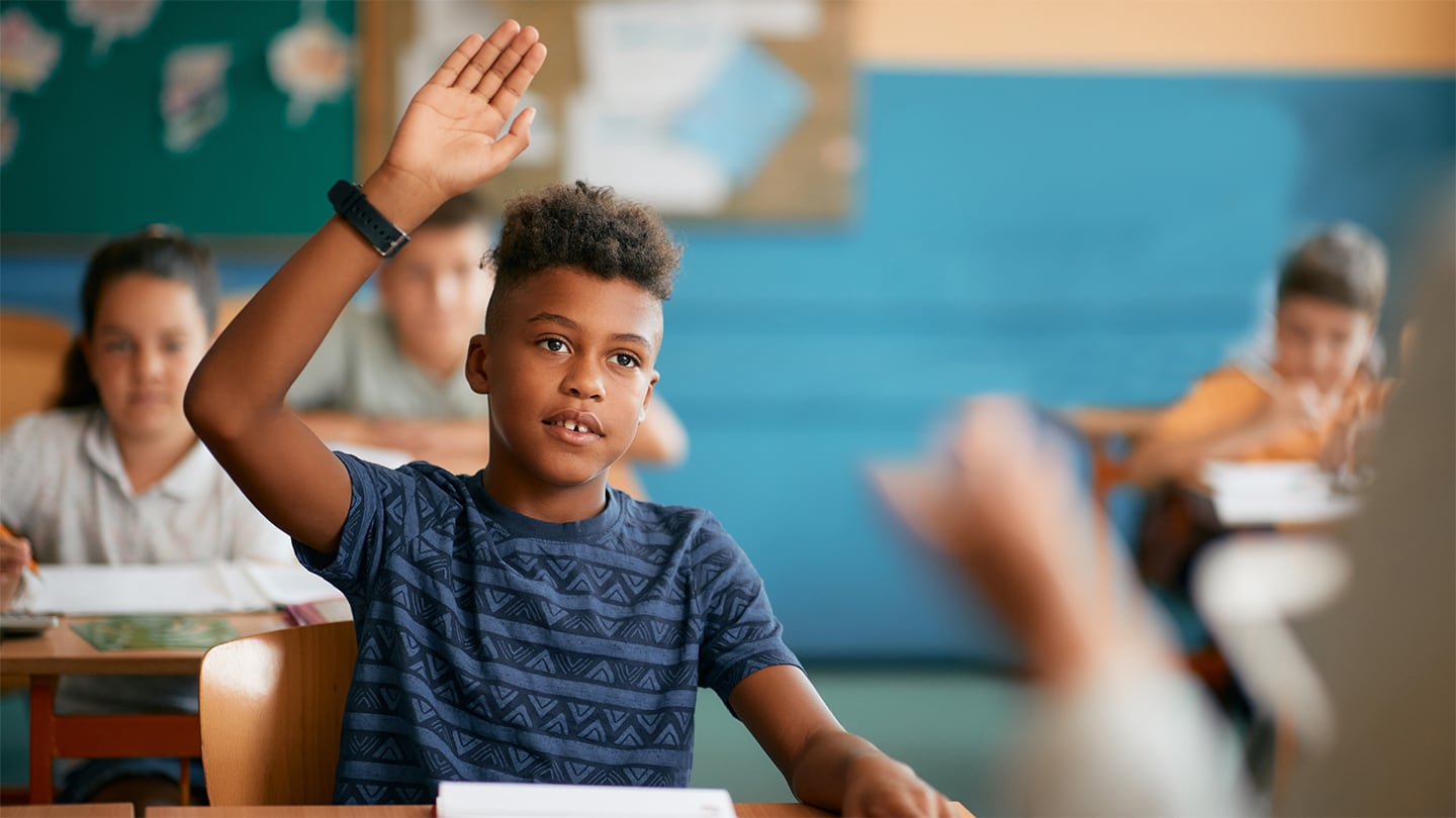 adolescent black man in classroom raising his hand
