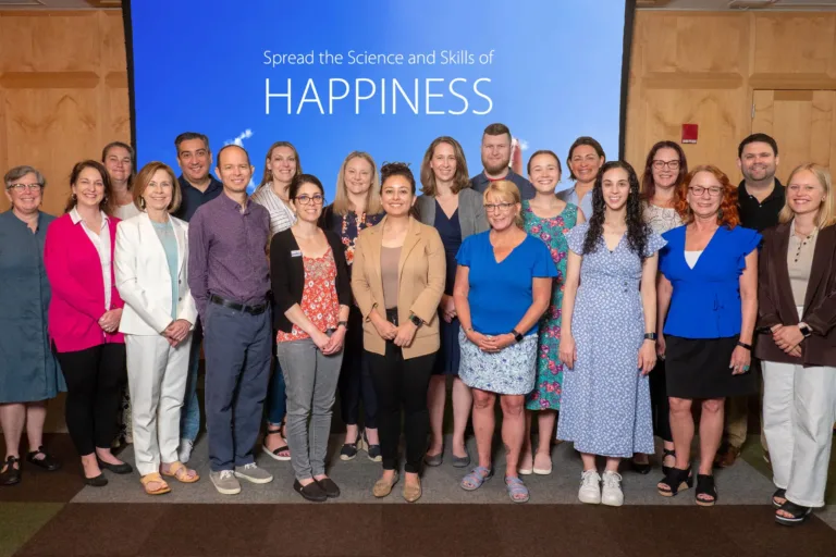 400x293_LIGroupShot Proof Positive Group standing with "Spread the Science and Skills of Happiness" in the background