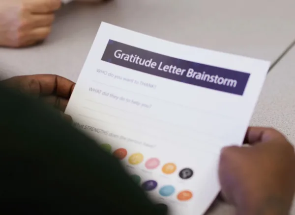 400x293_GratLetterBrainstorm Student holding a worksheet that says "Gratitude Letter Brainstorm"