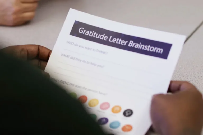 400x293_GratLetterBrainstorm Student holding a worksheet that says "Gratitude Letter Brainstorm"