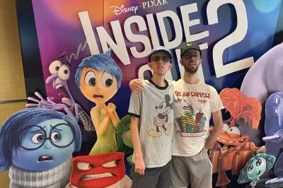 400x293_Disney+Autism_BlogPost Ryan and Justin are in front of Inside Out movie signage