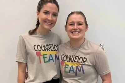 400x293_Layla autistic counselor Layla and her co counselor smile. Their t-shirts say "Counselor Team"