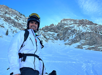 Oct14b_IG-VidBLOG-M4H-Mon-Shaan (400 x 293 px) Shaan is in his ski gear on a mountain with snow