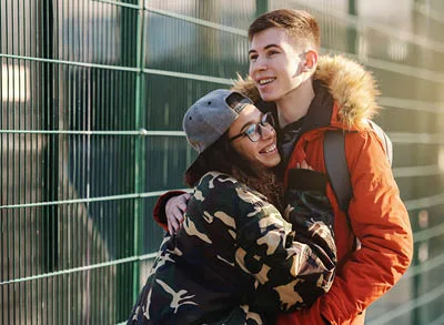 400x293_PWLoveBlog Teenage boy and girl outside smiling and hugging.