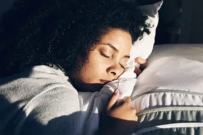 400x293_SleepSkill_Launch Image of woman with head on a pillow and eyes closed sleeping.