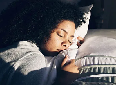 400x293_SleepSkill_Launch Image of woman with head on a pillow and eyes closed sleeping.