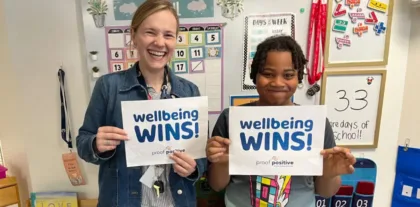 women holding "wellbeing wins" signs
