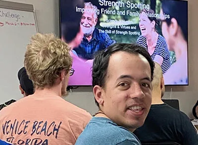 A participant looks back and smiles at the camera while in a classroom session about Strength Spotting.