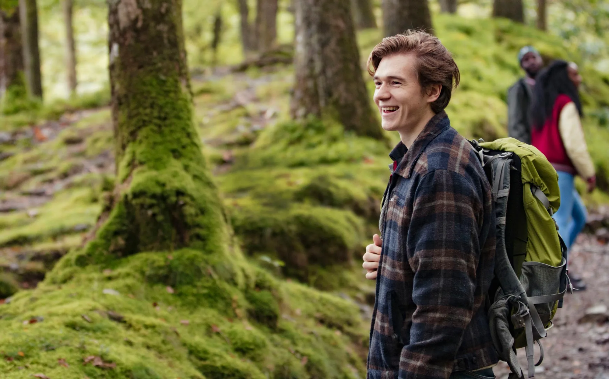 Smiling young man hiking in the woods with friends