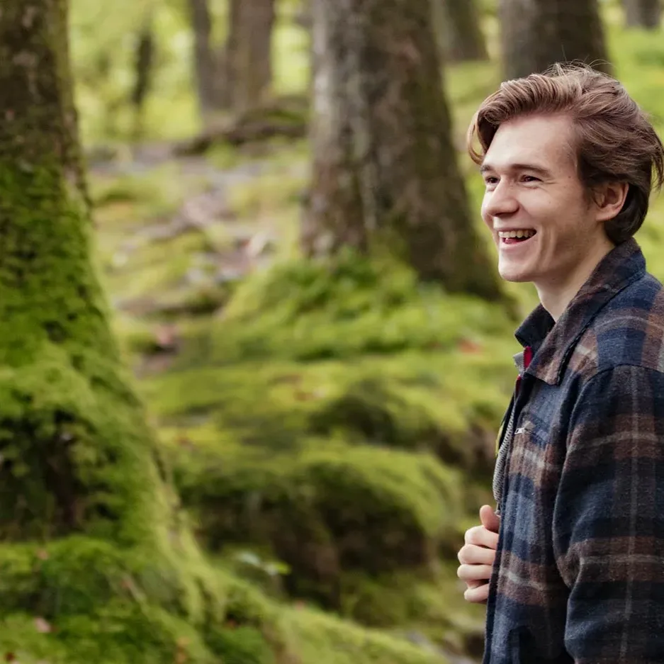 Smiling young man hiking in the woods with friends
