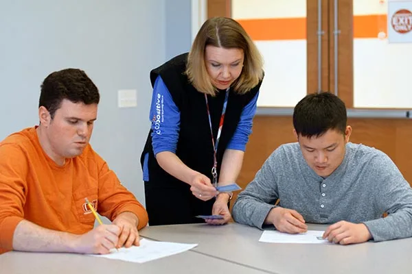 teacher with two students working on worksheets at a table