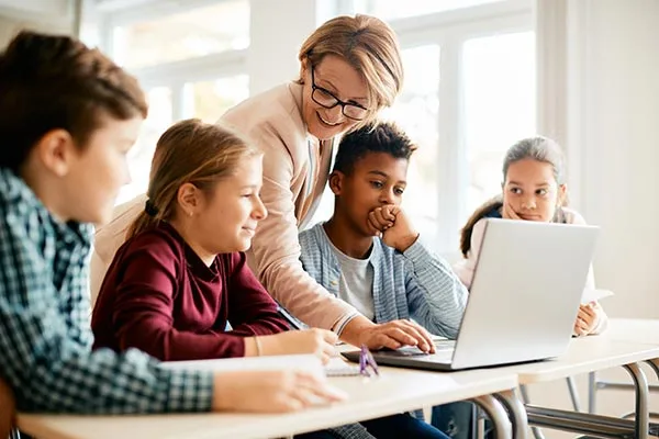 educator with students looking at a laptop