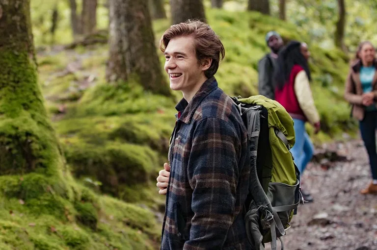 Smiling young man hiking in the woods with friends