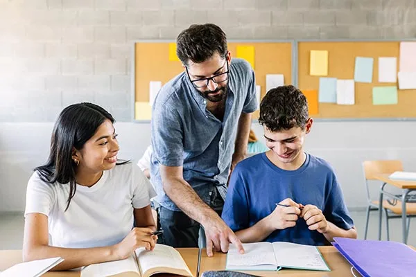 educator with students looking at workbooks