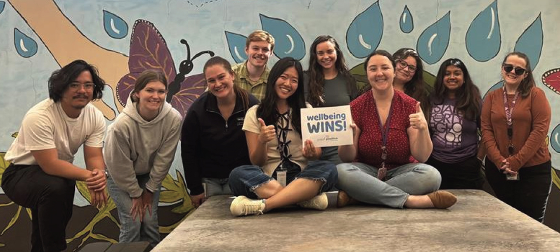 group of young people holding a wellbeing wins sign