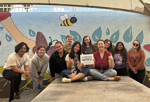 group of young people holding a wellbeing wins sign